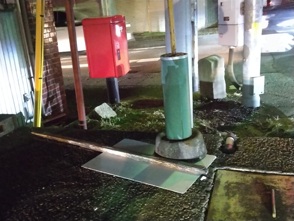 赤い郵便ポストと隣り合う谷田部町道路元標